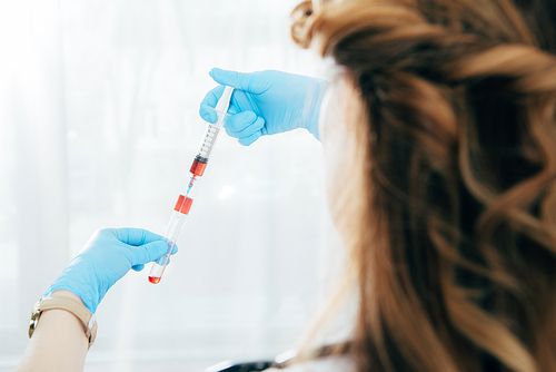 partial view of doctor in latex gloves holding syringe