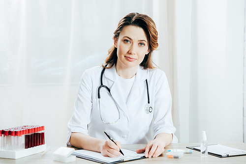 doctor in white coat writing on clipboard in clinic