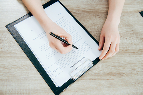 cropped view of donor signing registration form on wooden surface