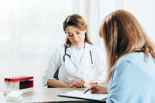 doctor in white coat and donor signing registration form