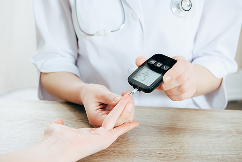 cropped view of donor and doctor measuring glucose level with glucometer