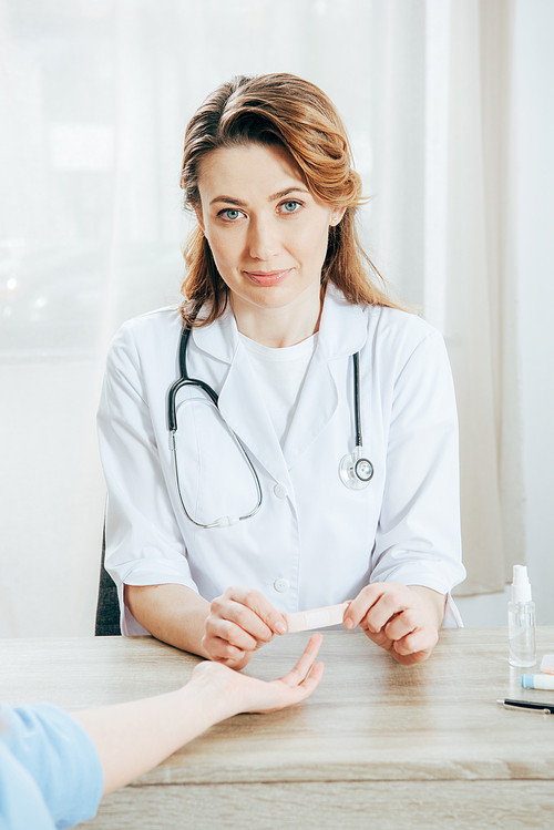 partial view of donor and doctor using adhesive bandage