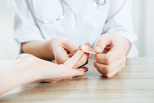 partial view of donor and doctor using adhesive bandage