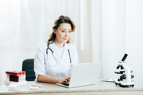 doctor in white coat with stethoscope using laptop in clinic