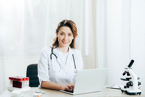 doctor in white coat with stethoscope using laptop in clinic