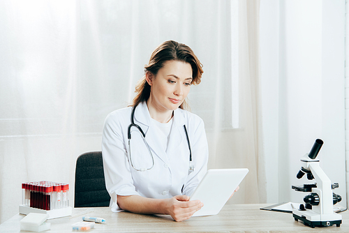 doctor in white coat with stethoscope using digital tablet in clinic