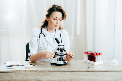 doctor in white coat using microscope in clinic