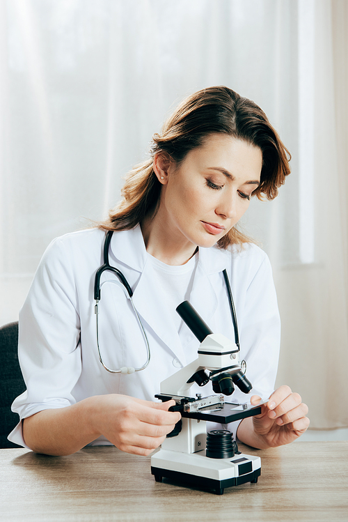 doctor in white coat using microscope in clinic