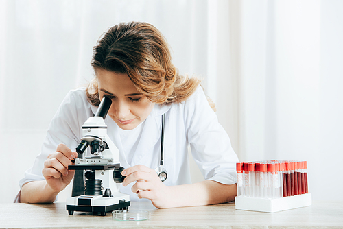 doctor in white coat using microscope in clinic