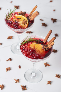 christmas cocktails with orange, pomegranate and cinnamon on marble table