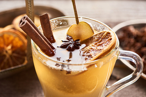 close up view of seasonal traditional pear mulled wine with spices and dried citrus in glass