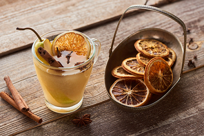 seasonal traditional pear mulled wine with spices in glass near dried citrus on wooden rustic table