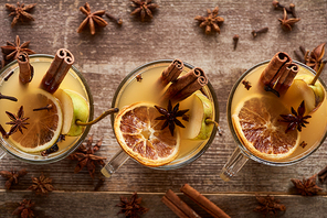 top view of seasonal pear mulled wine cocktails with spices and dried citrus on wooden rustic table