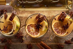 top view of seasonal pear mulled wine cocktails with spices and dried citrus on wooden rustic table