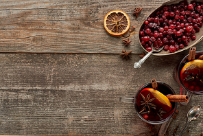 top view of red spiced mulled wine with berries, anise, orange slices and cinnamon on wooden rustic table