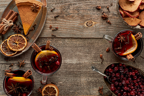 top view of piece of pie and red spiced mulled wine with berries, anise, orange slices and cinnamon on wooden rustic table