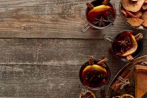 top view of piece of pie and red spiced mulled wine with berries, anise, orange slices and cinnamon on wooden rustic table