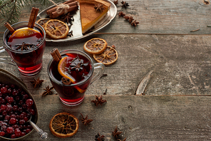 red spiced mulled wine near berries, anise, orange slices and cinnamon on wooden rustic table with copy space