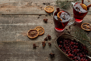 red spiced mulled wine with fir branch, berries, anise, orange slices and cinnamon on wooden rustic table