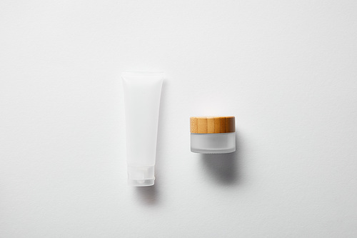 top view of jar with wooden cap and cream tube on white