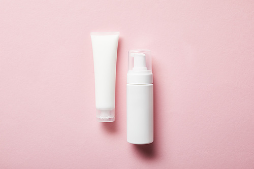 top view of cream tube with hand cream and cosmetic dispenser on pink