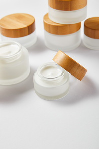 glass jars with cream and wooden caps on white
