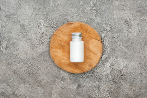 top view of coconut beauty product in bottle on wooden board on grey textured background