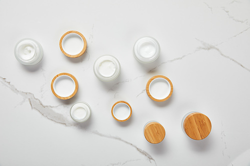 top view of jars with cosmetic cream on white surface