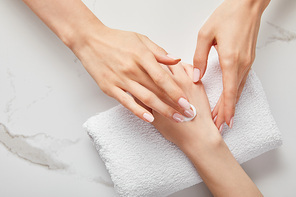 cropped view of woman applying cream on white surface with towel