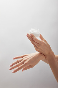 cropped view of woman hands holding jar with cream isolated on white