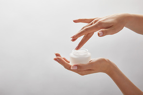 cropped view of woman hands holding jar with cream isolated on white