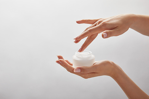 cropped view of woman hands holding jar with cream isolated on white