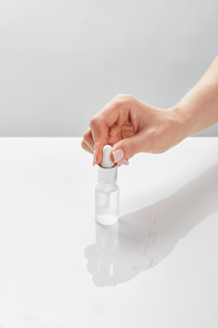 cropped view of woman hand with cosmetic glass bottle