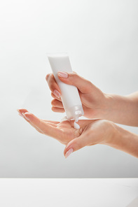 cropped view of woman holding cosmetic tube in hands, applying cream on skin