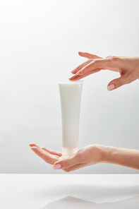 cropped view of woman holding cosmetic cream tube in hands