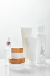 white surface with glass bottles, cream in tubes, jars and cosmetic dispenser