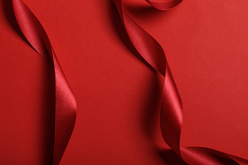close up of curved silk red ribbons on red background