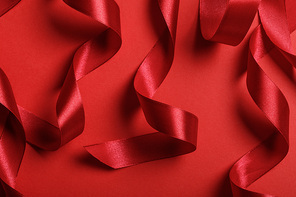 close up of curved satin red ribbons on red background
