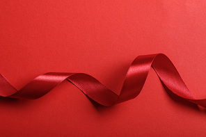 top view of wavy silk red ribbon on red background with copy space