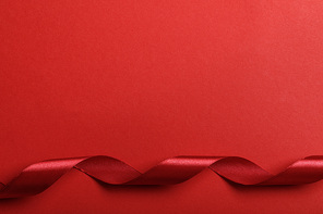 top view of curved silk red ribbon on red background