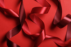 close up of silk burgundy and red ribbons on red background