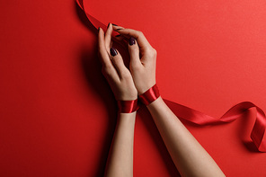 top view of woman tied with satin ribbon on red background