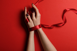 partial view of woman tied with satin ribbon on red background
