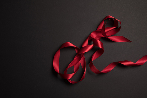 top view of red satin ribbon on black background with copy space