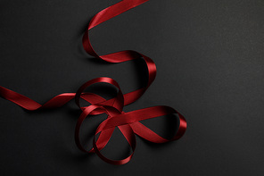 top view of red satin wavy ribbon on black background with copy space