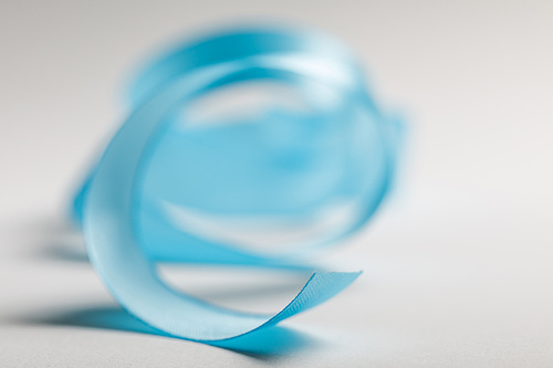 selective focus of curved blue satin ribbon on grey background