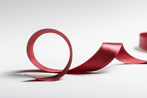 silk curved burgundy ribbon on grey background
