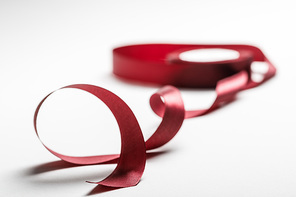 selective focus of satin wavy burgundy ribbon with spool on grey background