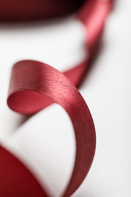 close up of silk wavy burgundy ribbon on grey background