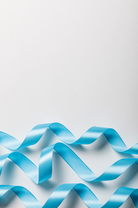 top view of blue wavy satin ribbons on grey background with copy space